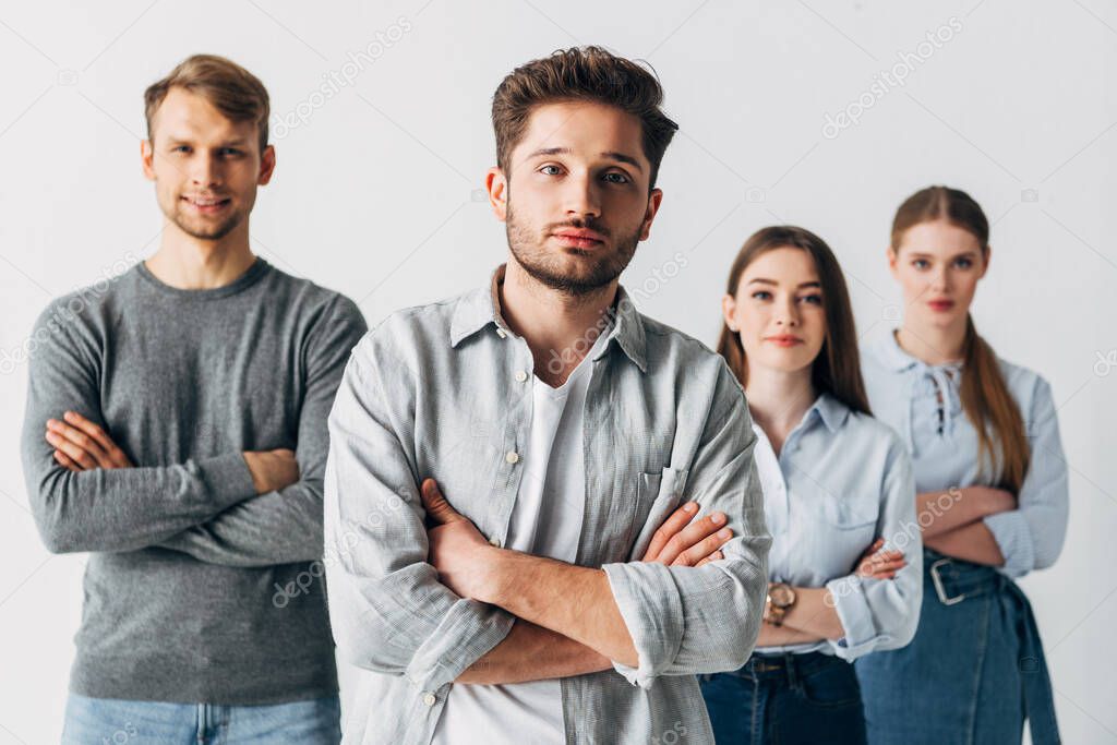 Selective focus of coworkers with crossed arms looking at camera in office 