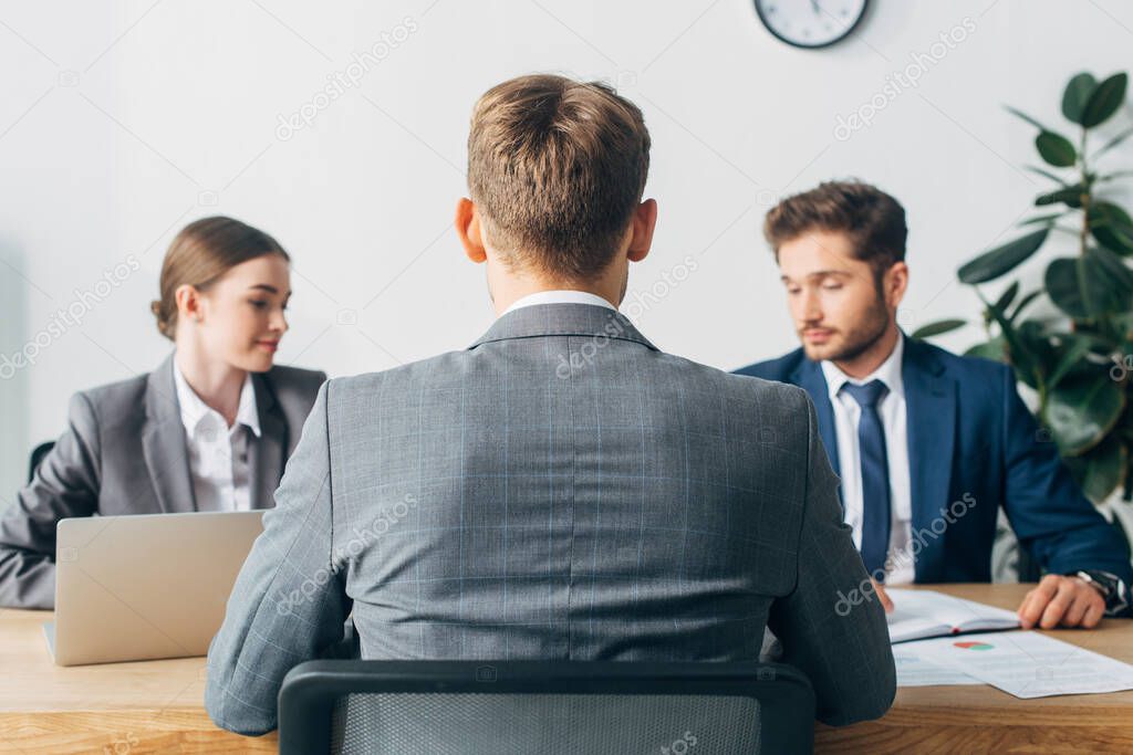 Selective focus of employee sitting at table during job interview with recruiters