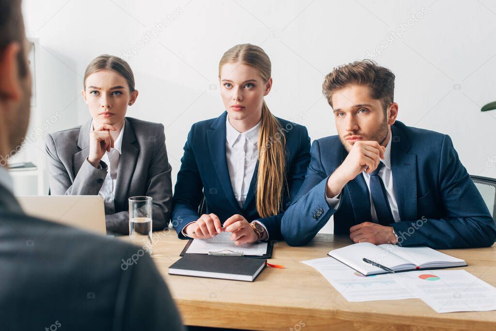 Selective focus of recruiters looking at employee during job interview in office 