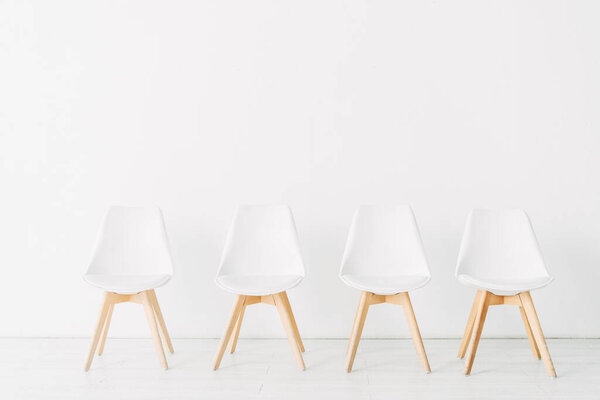 Row of chairs near white wall in office 