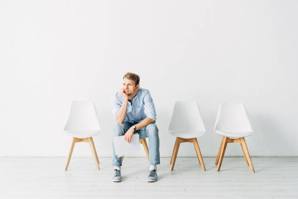 Красивый работник с рукой у подбородка держа резюме во время пребывания в офисе
 