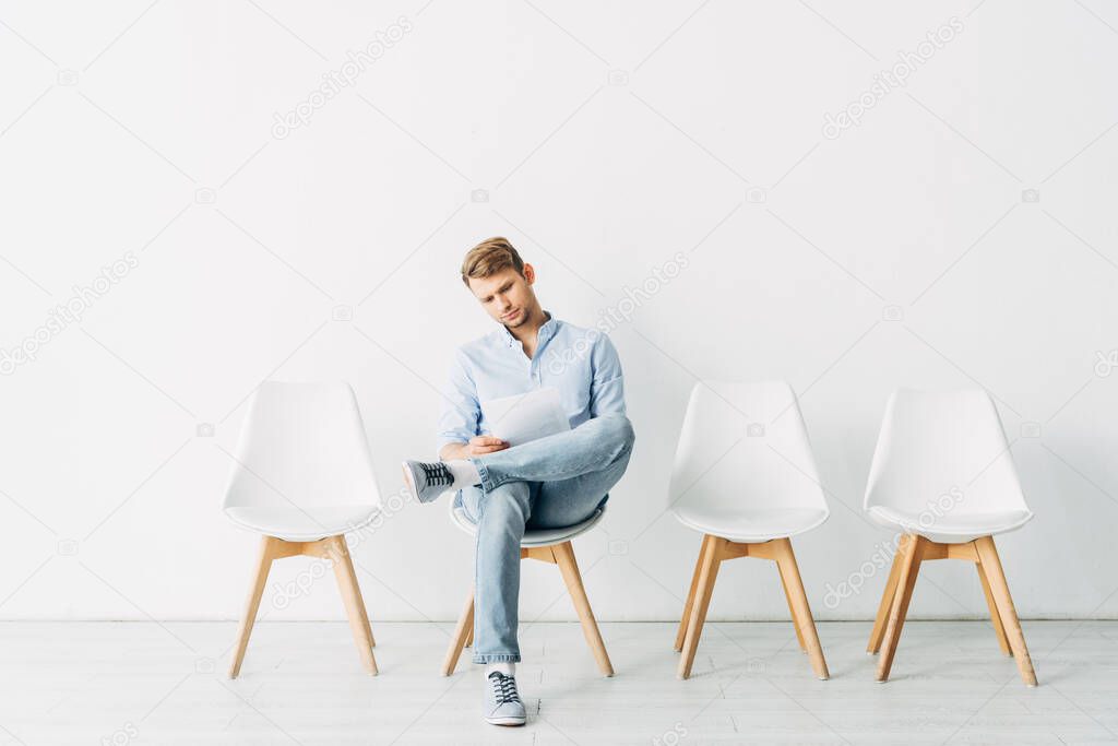 Handsome man reading resume while waiting for job interview 
