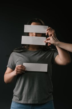Gencin ön görüntüsü artı siyah arka plandaki boş kartların altında saklanan kadın.