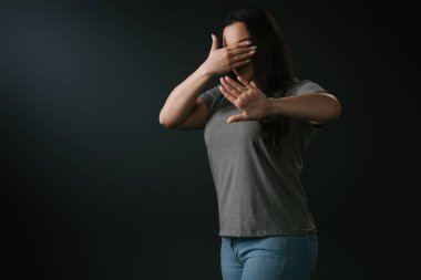 Artı cüsseli kız, siyah üzerine izole edilmiş dur hareketi ile körlük ve inkarı ifade ediyor.