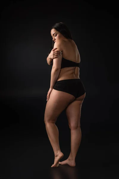 stock image Full length view of plus size girl hiding body with shame on black background