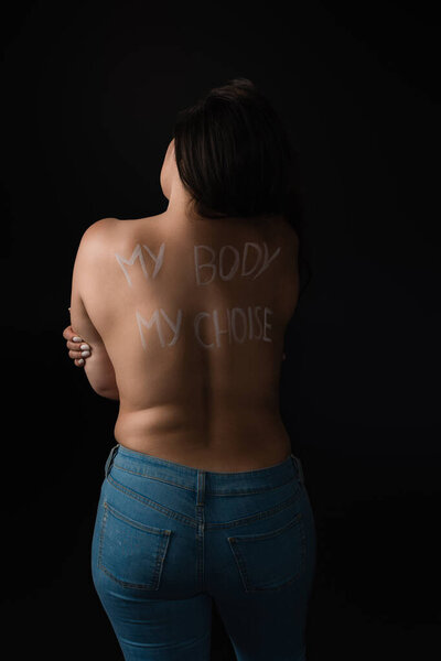 Back view of plus size model with lettering My Body My Choice on body isolated on black 
