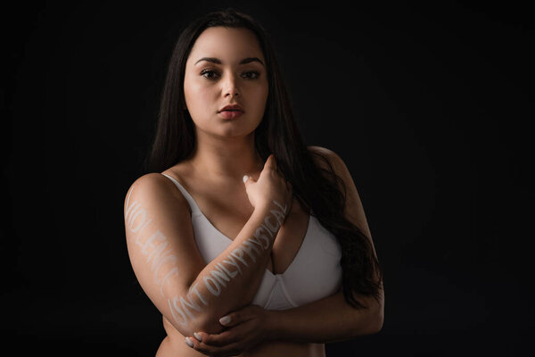 Beautiful plus size model covering bust with hand with lettering Violence Is not Only Physical isolated on black