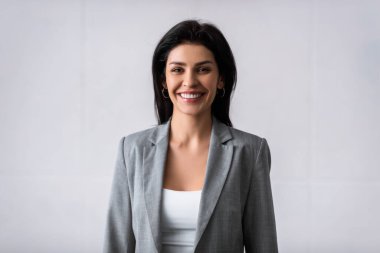 Beyaz kameraya bakarken gülümseyen neşeli iş kadını