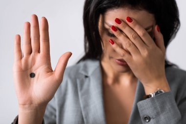 selective focus of sad businesswoman showing hand with black dot on palm and covering eyes isolated on white, domestic violence concept  clipart
