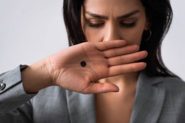 upset businesswoman with black dot on palm covering mouth isolated on white, domestic violence concept  clipart
