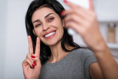 Yüzünde morluklar olan gülümseyen bir kadının selfie çekerken barış işareti göstermesi, aile içi şiddet kavramı. 
