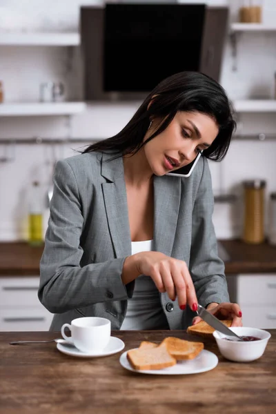 Bela Empresária Segurando Faca Perto Pão Torrado Enquanto Conversa Smartphone — Fotografia de Stock