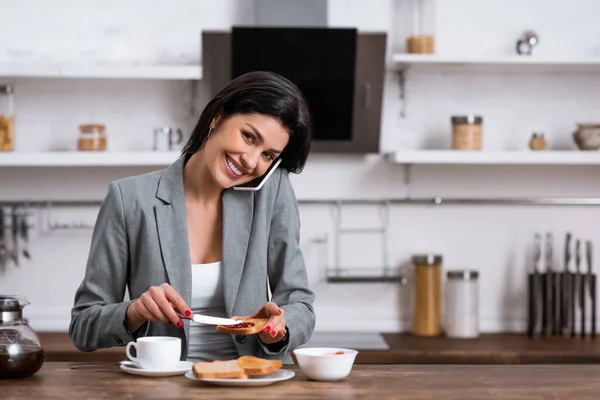 Vrolijke Zakenvrouw Met Toast Brood Tijdens Het Praten Smartphone Verbergen — Stockfoto