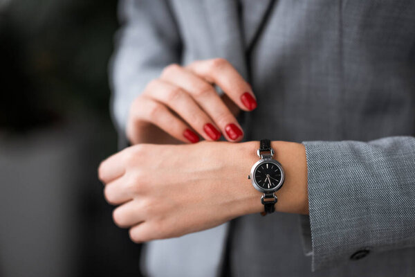 cropped view of businesswoman with bruise on hand touching watch, domestic violence concept 