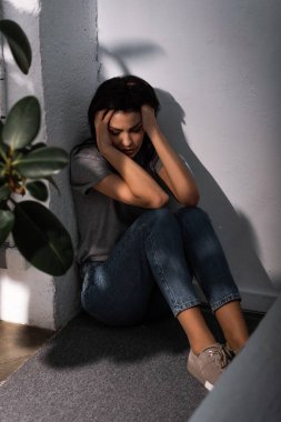 selective focus of scared woman with bruise on face sitting on floor at home, domestic violence concept  clipart