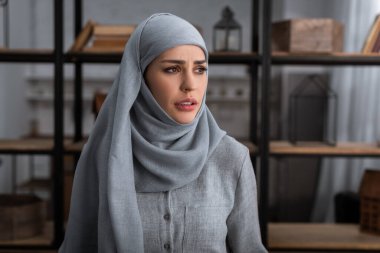 tesettürlü müslüman kadın oturma odasına bakıyor, aile içi şiddet kavramı.  