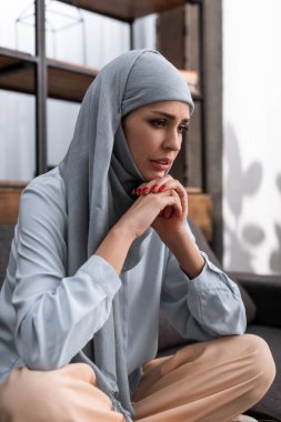 tesettürlü endişeli Arap kadın elleri sımsıkı oturuyor, aile içi şiddet kavramı  