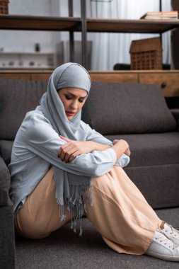 Sinirli Arap kadın oturma odasında yerde oturuyor, aile içi şiddet kavramı.  