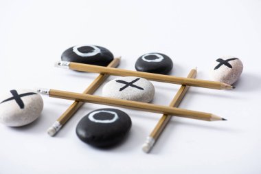 tic tac toe game with grid made of pencils and pebbles marked with naughts and crosses on white surface clipart