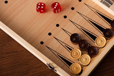 KYIV, UKRAINE - JANUARY 30, 2019: top view of backgammon board with checkers and dice pair on wooden table clipart