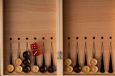 KYIV, UKRAINE - JANUARY 30, 2019: top view of wooden backgammon board with dice pair and checkers clipart