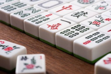 KYIV, UKRAINE - 30 HAZİRAN 2019: Tahta masa üzerinde işaretleri ve karakterleri olan beyaz mahjong oyununun seçici odak noktası