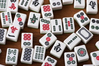 KYIV, UKRAINE - 30 HAZİRAN 2019: Ahşap masa üzerinde işaretleri ve karakterleri olan beyaz mahjong oyun fayanslarının üst görünümü