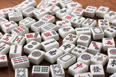 KYIV, UKRAINE - 30 HAZİRAN 2019: Tahta masa üzerinde işaretleri ve karakterleri olan beyaz mahjong oyununun seçici odak noktası