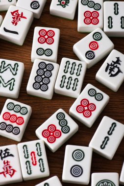 KYIV, UKRAINE - 30 HAZİRAN 2019: Ahşap masa üzerinde işaretleri ve karakterleri olan beyaz mahjong oyun fayanslarının üst görünümü