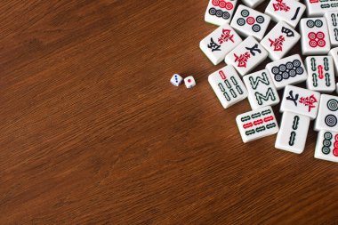 KYIV, UKRAINE - 30 HAZİRAN 2019: Tahta masadaki mahjong oyun taşlarının yanındaki zar çiftinin üst görünümü