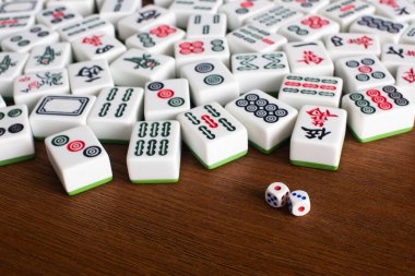 KYIV, UKRAINE - 30 HAZİRAN 2019: Tahta masadaki mahjong oyun taşlarının yanındaki zar çiftinin seçici odak noktası