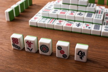 KYIV, UKRAINE - 30 HAZİRAN 2019: Ahşap masa üzerindeki mahjong oyunu fayanslarından yapılmış sıraların ve piramidin seçici odağı