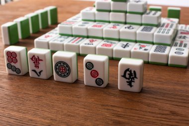 KYIV, UKRAINE - 30 HAZİRAN 2019: Ahşap masa üzerindeki mahjong oyunu fayanslarından yapılmış sıraların ve piramidin seçici odağı