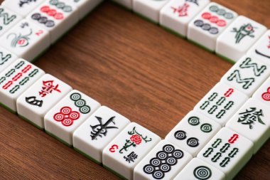 KYIV, UKRAINE - 30 HAZİRAN 2019: Kare çerçevenin seçici odak noktası ve ahşap masa üzerindeki sıra sıra mahjong oyun fayansları