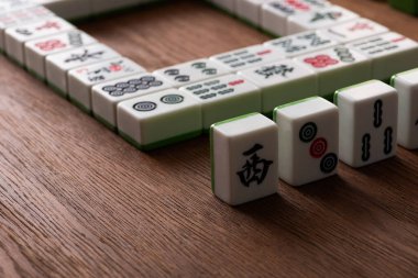 KYIV, UKRAINE - 30 HAZİRAN 2019: Tahta masa üzerinde işaretleri ve karakterleri olan mahjong oyun fayanslarının seçici odağı