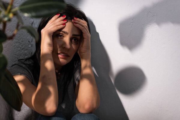 selective focus of depressed woman with bruise touching face, domestic violence concept 