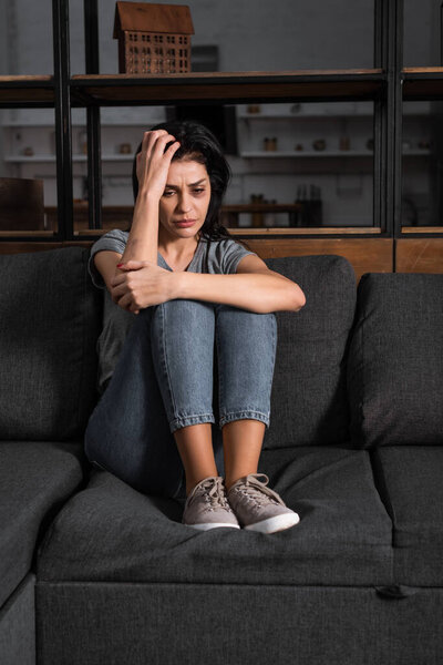 upset woman with bruise on face sitting on sofa, domestic violence concept 