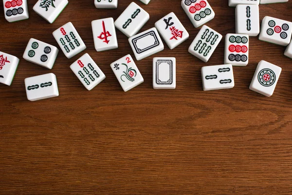 KYIV, UKRAINE - 30 HAZİRAN 2019: Ahşap masa üzerinde işaretleri ve karakterleri olan beyaz mahjong oyun fayanslarının üst görünümü