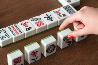KYIV, UKRAINE - 30 HAZİRAN 2019: Ahşap masadan mahjong oynayan bir kadının kısmi görüntüsü