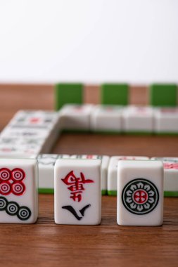 KYIV, UKRAINE - 30 HAZİRAN 2019: Tahta yüzeyde izole edilmiş işaretler ve karakterlerle mahjong oyun fayanslarının seçici odağı