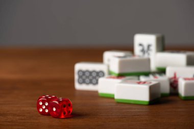 KYIV, UKRAINE - JANUARY 30, 2019: selective focus of dice pair near mahjong tiles on wooden surface isolated on grey clipart