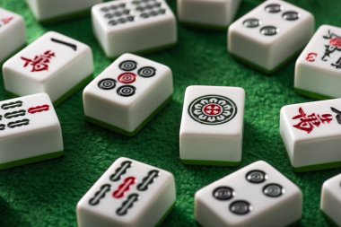 KYIV, UKRAINE - 30 HAZİRAN 2019: Yeşil kadife yüzeyinde işaretleri ve sembolleri olan beyaz mahjong oyununun seçici odak noktası
