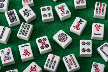 KYIV, UKRAINE - 30 HAZİRAN 2019: Yeşil kadife yüzeyinde işaretleri ve karakterleri olan beyaz mahjong oyun fayanslarının üst görünümü