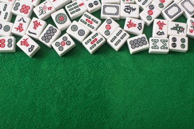 KYIV, UKRAINE - 30 HAZİRAN 2019: Yeşil kadife yüzeyinde işaretleri ve karakterleri olan beyaz mahjong oyun fayanslarının üst görünümü