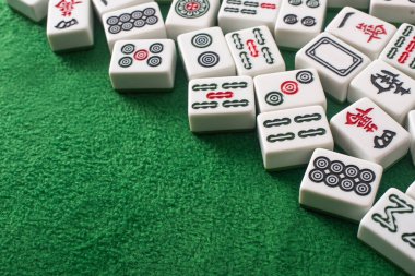 KYIV, UKRAINE - 30 HAZİRAN 2019: Yeşil kadife yüzeyinde işaretleri ve karakterleri olan beyaz mahjong oyunu fayansları