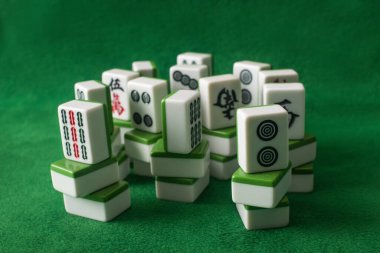 KYIV, UKRAINE - 30 Ocak 2019: yeşil kadife üzerine istiflenmiş mahjong oyun fayanslarının seçici odak noktası
