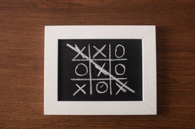 Tahtadaki tic tac toe oyununun en üst görünümü tahta yüzeydeki haç sırasının üzerini çizerek