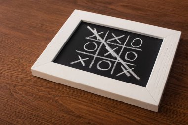 tic tac toe game on blackboard with crossed out row of crosses on wooden surface clipart