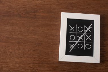 Tahtadaki tic tac toe oyununun en üst görünümü tahta yüzeydeki haç sırasının üzerini çizerek