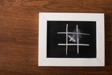 Tahtada tebeşir ızgarası ve ahşap yüzey üzerinde çapraz çizgi ile tic tac toe oyununun üst görünümü